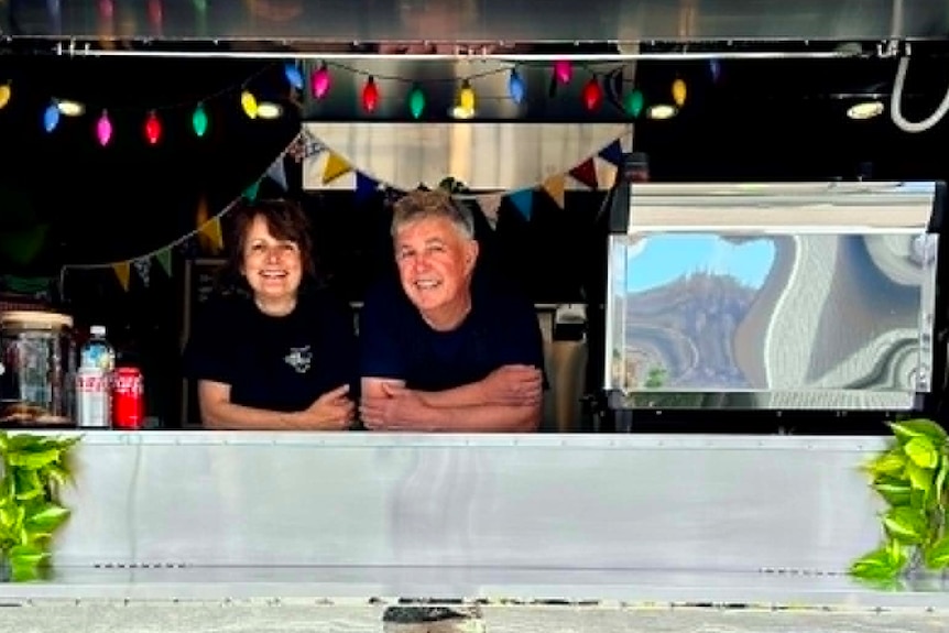 A couple stands inside a food delivery truck.