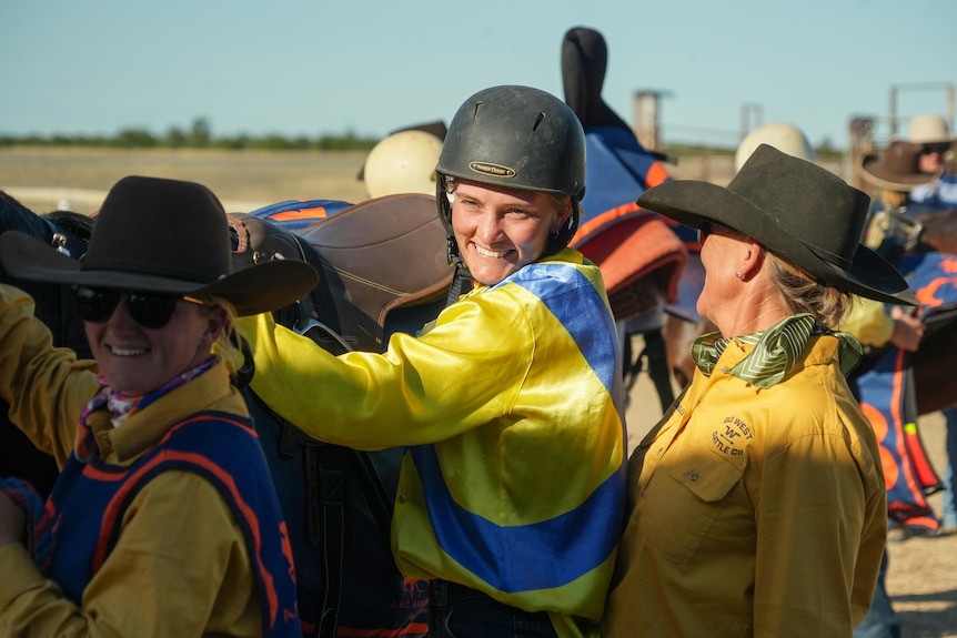 A female jockey smiles after dismounting her horse 