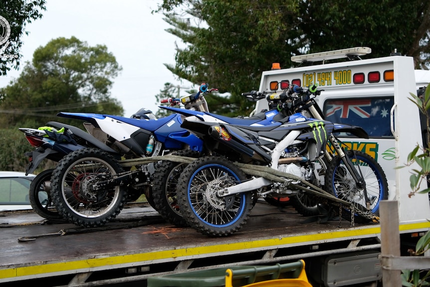 Motorbikes covered in stickers on the back of a police truck.