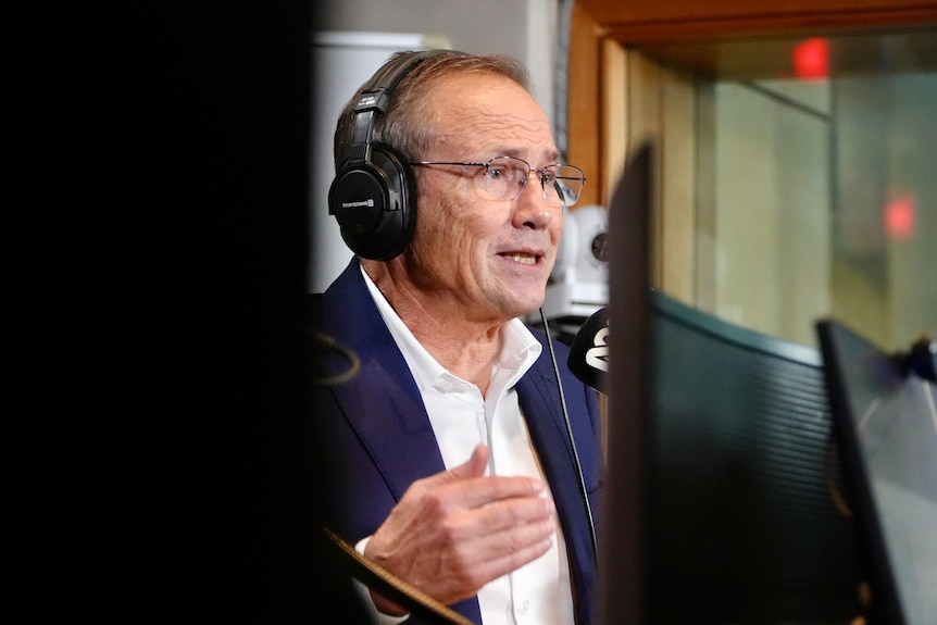 A close-up shot of WA Premier Roger Cook speaking in a radio studio wearing headphones, with monitors around him.