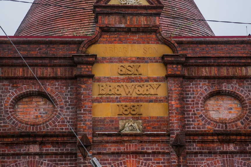 a red brick building with grey skies and green signage