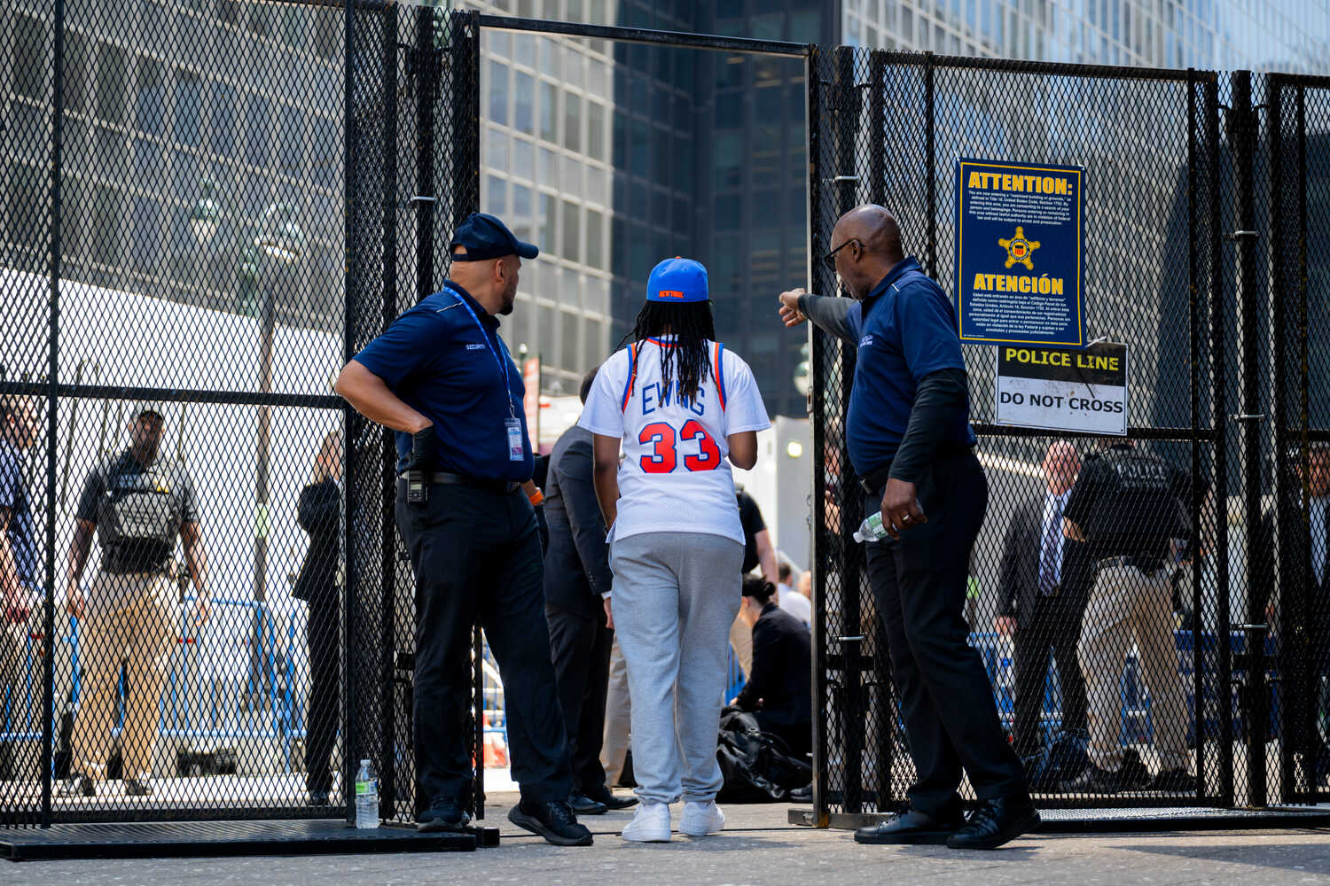 A person in a white Patrick Ewing Knicks jersey walks through a gate.