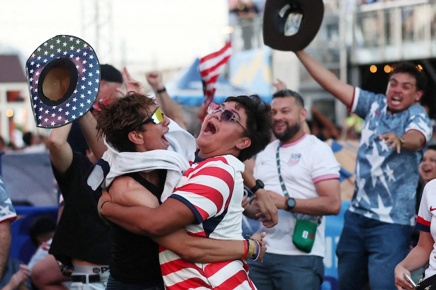 man wearing USA shirts and hats jump, cheer and hug