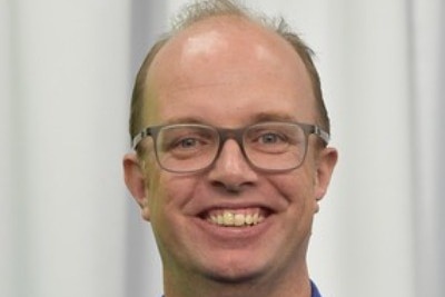 A bald man wearing glasses and a blue polo shirt