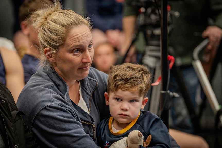 Two people in the crowd at a media conference.