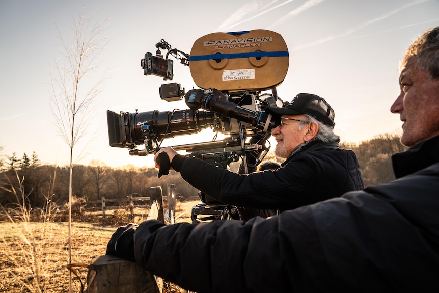 A man looks through the lense of a film camera.