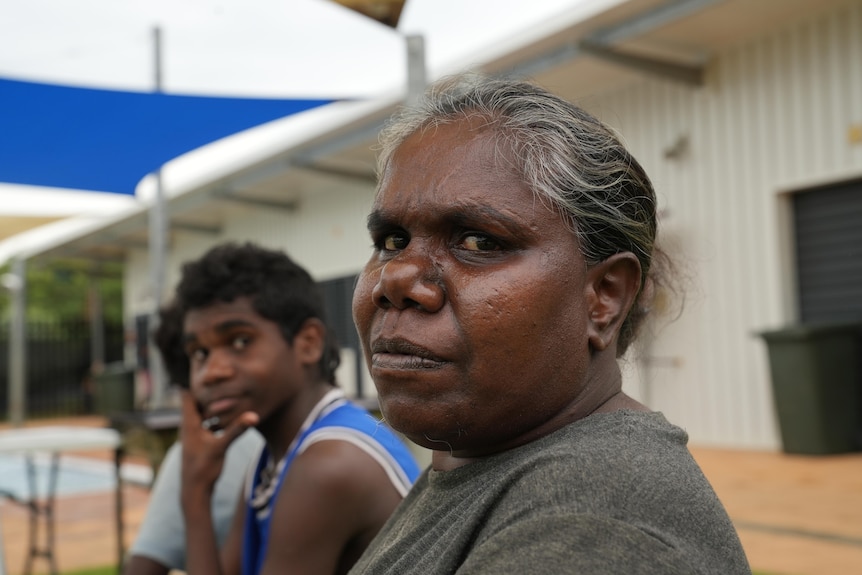 Indigenous woman with grey hair sitting with children