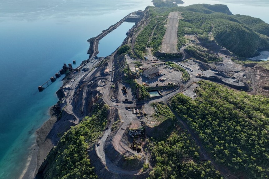 A view from the air of an island with dirt airstrip, small port and industry