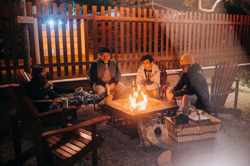 men sitting around fire pit