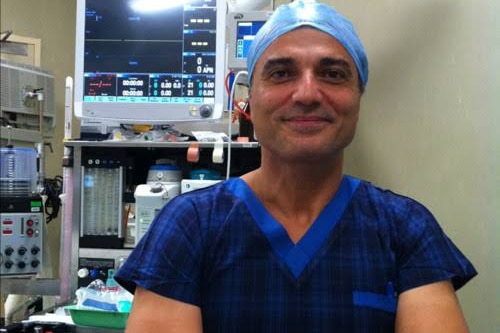 A man in scrubs stands in a medical room.
