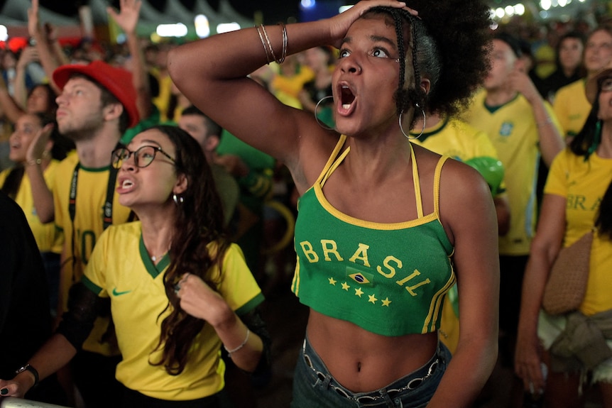 two women in yellow and green brasil clothes gasp in horror/shock