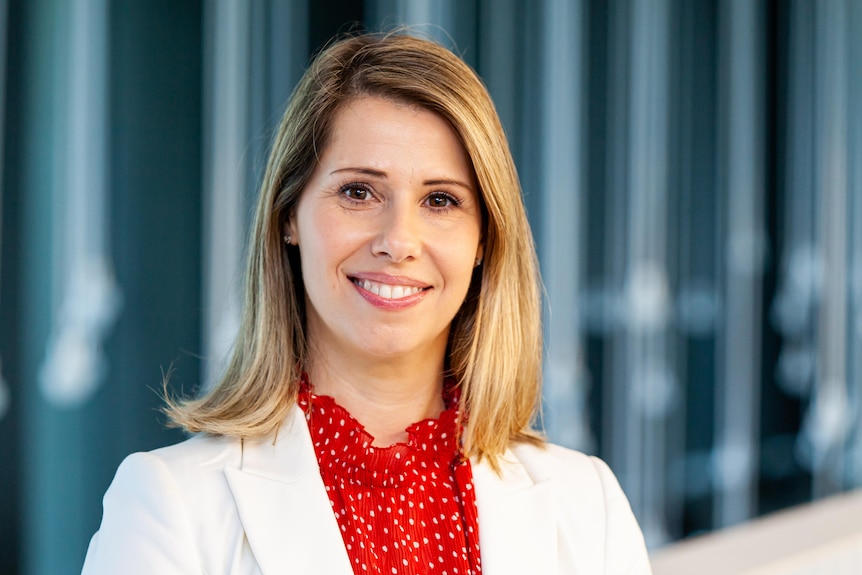 woman head shot wearing red shirt and white blazer