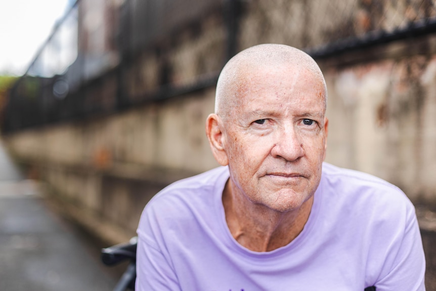 A close-up portrait of a bald man looking straight at the camera