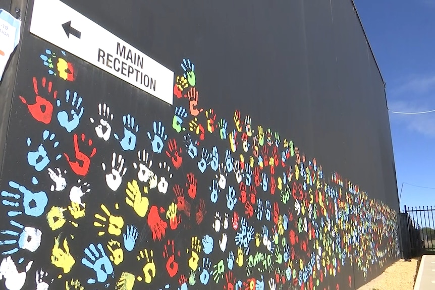 a mural of hands in different colours on the side of a building in orange