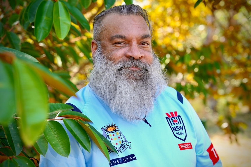 A man with full thick beard smiles to the camera.
