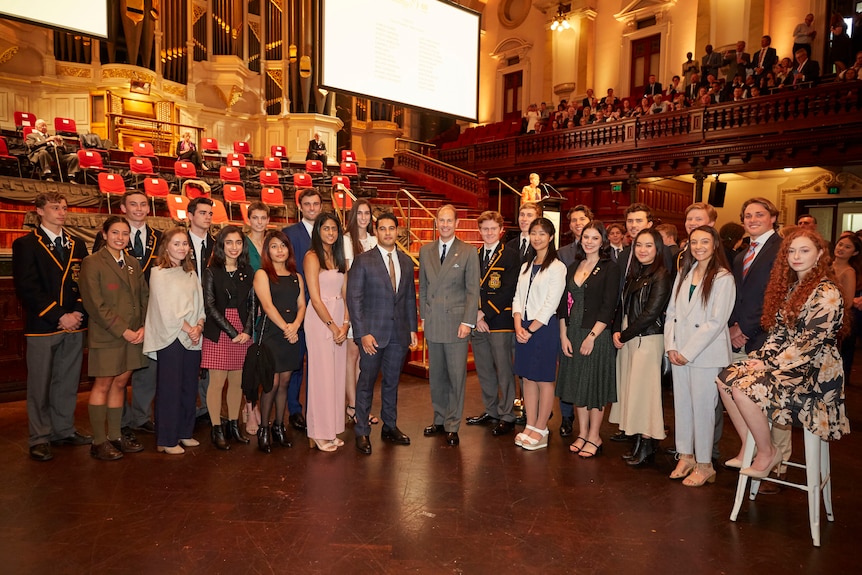 Marc, left, and Prince Edward, right, pose for a photo with about 20 other people.