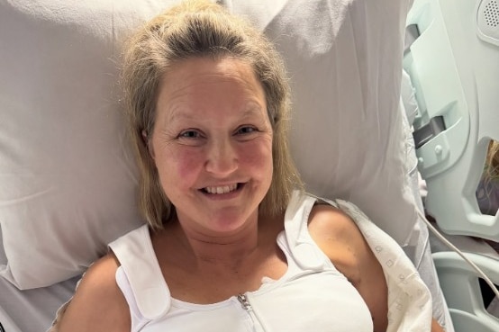A woman smiles while lying in a hospital bed.