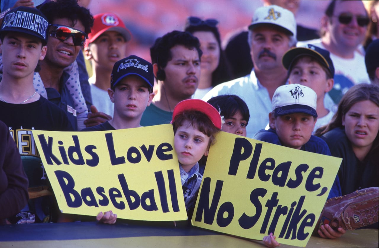 A group of baseball fans, one of whom holds up signs urging players not to strike, during an Aug. 11, 1994 MLB game.