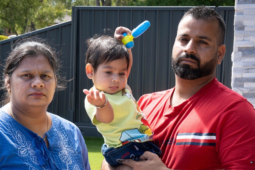 A woman and a man holding a young child in front of a house