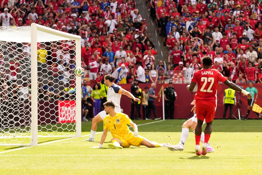 Sead Kolasinac deflects the ball towards the crossbar as the goalkeeper lays on the ground