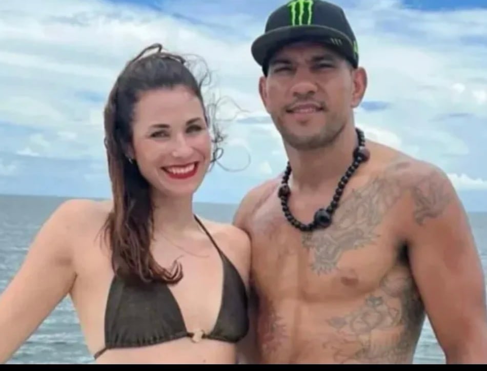A woman in a bikini and a shirtless man in a Monster Energy drink hat pose for a photo.