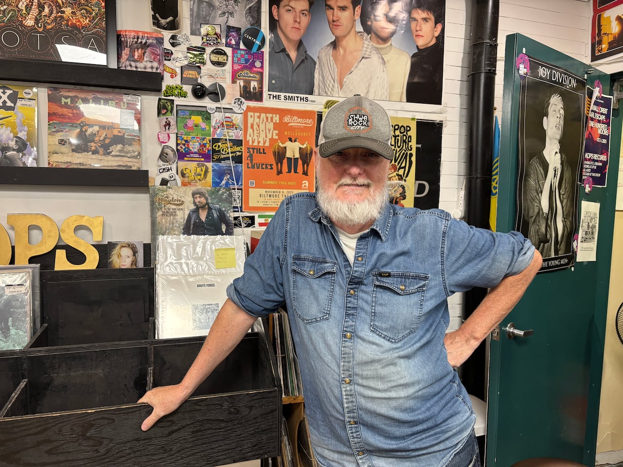 Photo of a man in a baseball cap standing in a record store.