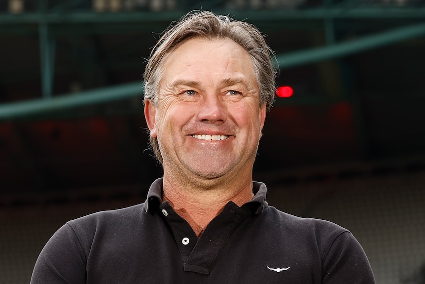 A man wearing a black shirt smiles.