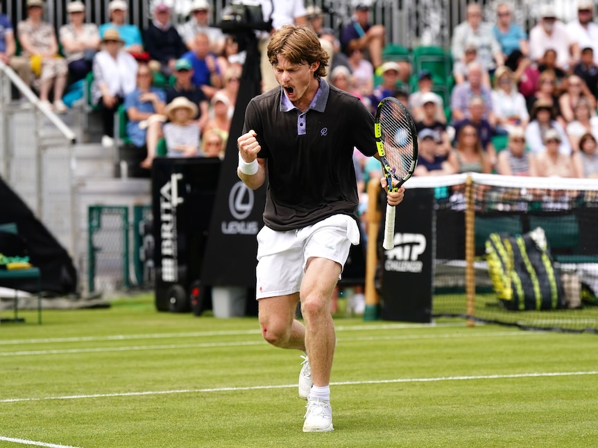 A tennis player pumps his fist and screams in joy after winning a point.