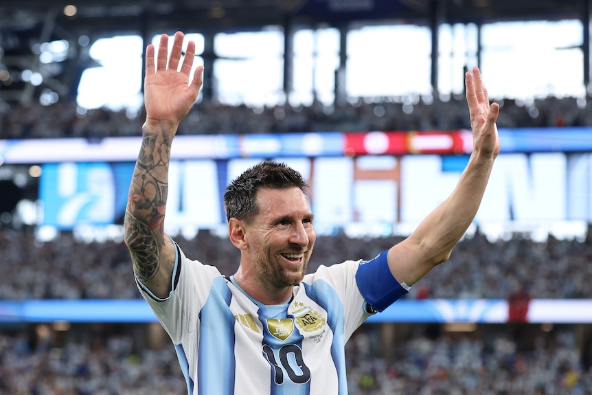 Lionel Messi holds his hands up and smiles