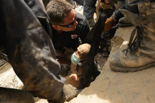 U.S. firefighters from the Fairfax County pull a survivor from the rubble of a building that collapsed in the earthquakes in La Guaira, Venezuela, Sunday, June 28, 2026. (AP Photo/Matias Delacroix)