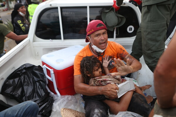 A rescuer carries a girl pulled from the rubble four days after twin earthquakes struck La Guaira, Venezuela, Sunday, June 28, 2026. (AP Photo/Pedro Mattey)