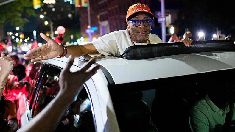 Spike Lee is driven through a crowd of New York Knicks supporters