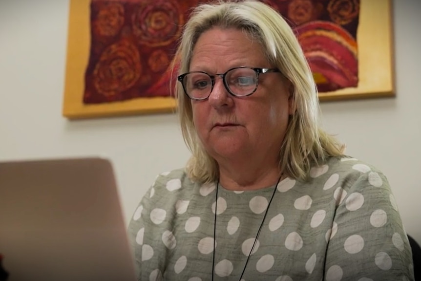 a woman stares at a computer screen