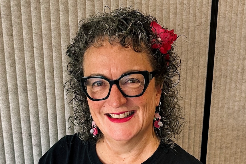 A woman with curly hair wears a black tshirt that says Libraries Change Lives.