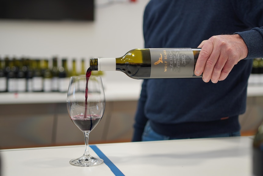 Wine being poured into a glass on a kitchen bench