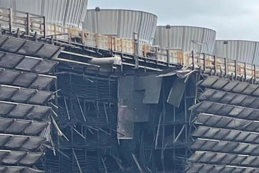 A large hole blown in the side of an industrial building.