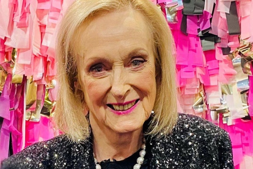 Elderly lady in front of a pink backdrop