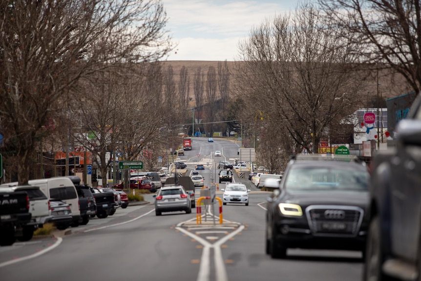 An image of a small alpine town main street with cars passing through