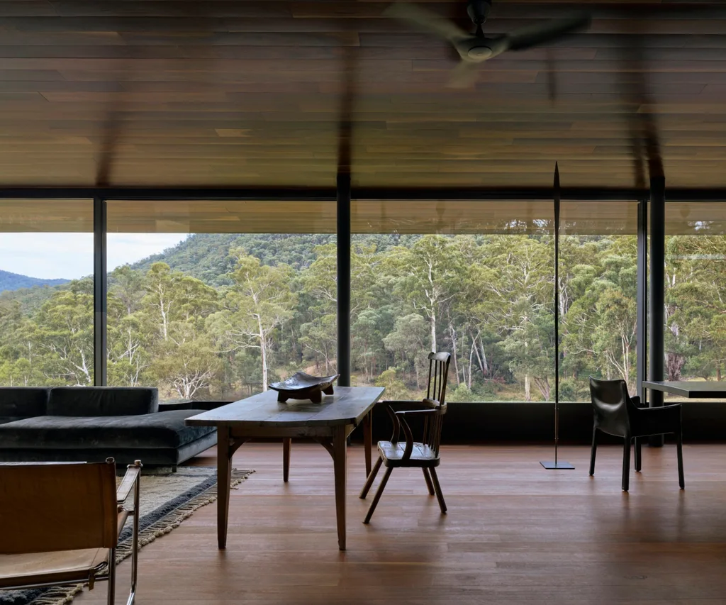 With windows framing the forest beyond, the kitchen/dining area includes a vintage table, chair and platter