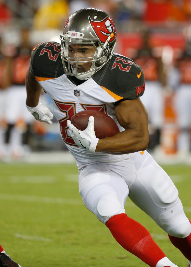 A football player in a Buccaneers uniform running with the ball.