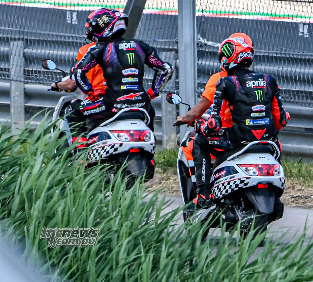 Aprilia riders travel on scooters after the opening-lap crash at Balaton Park.