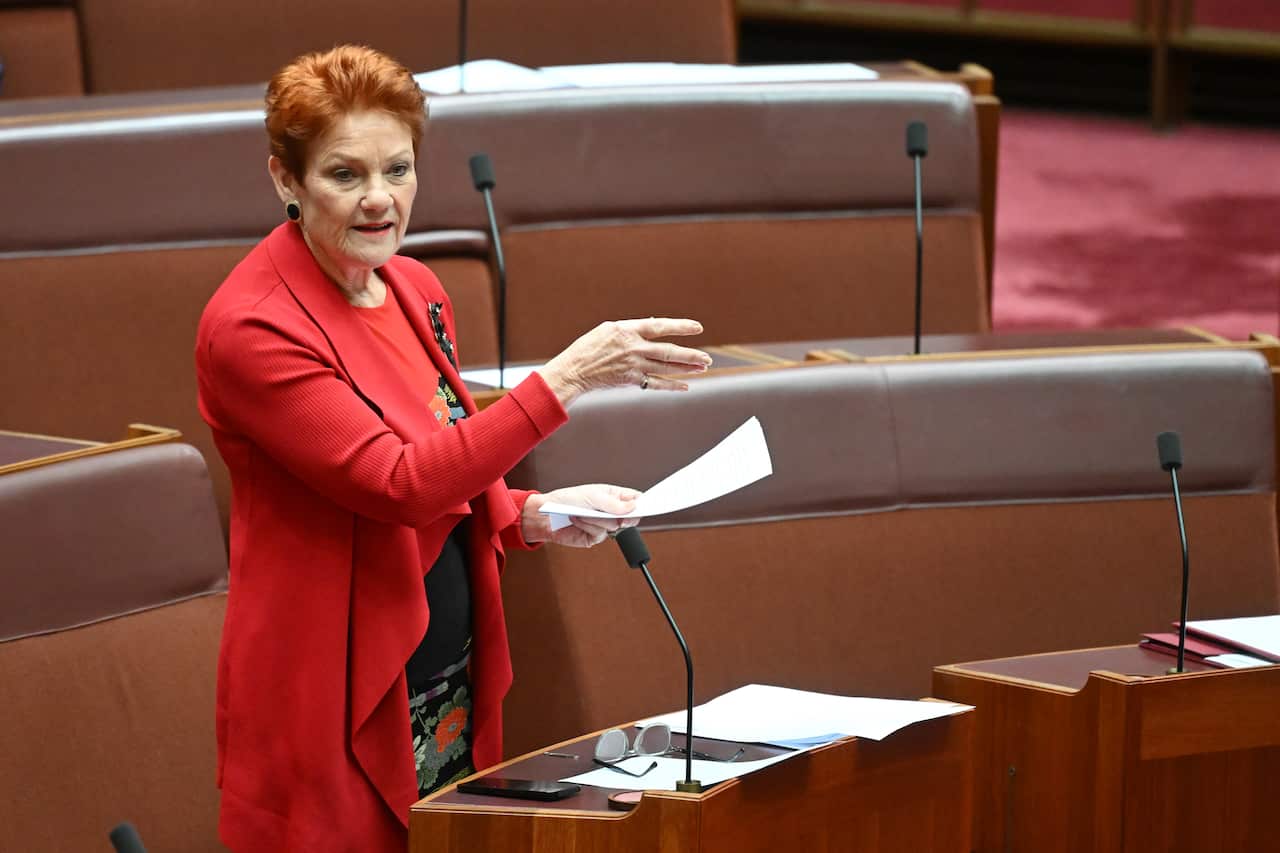 A woman in a red suit with orange hair in the maroon senate