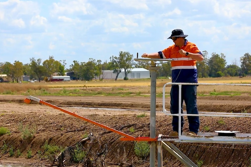 A man in high vis lowers a sensor into a dam.