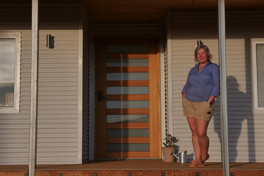 woman with short blonde hair stand on the veranda of a house
