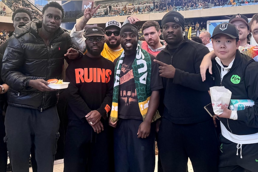 A group of men shoulder to shoulder at a packed stadium