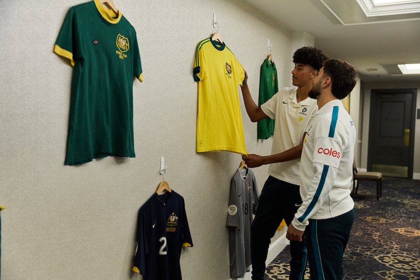 Jacob Italiano and Lucas Herrington of the 2026 World Cup Socceroos squad look at some of the jersey
