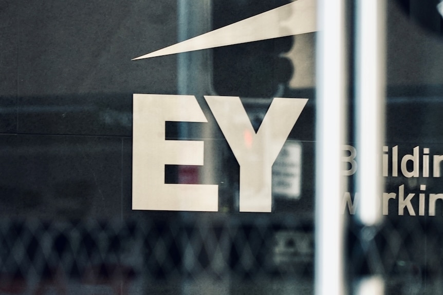 A white EY logo on glass.