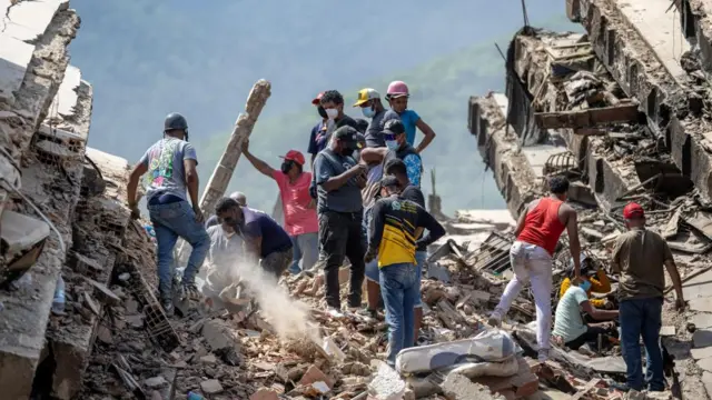 People look through the rubble of a collapsed building