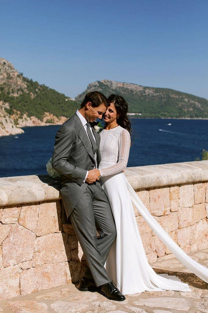 Rafa Nadal and Xisca Perello lean against a sandstone wall looking out on the sea and mountains after being married.