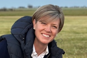 A woman smiling at camera with grass in background